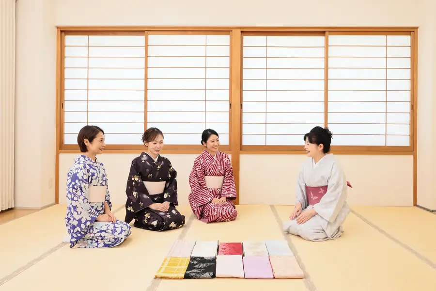 畳の教室で、着物姿の4人が並んで座っている様子